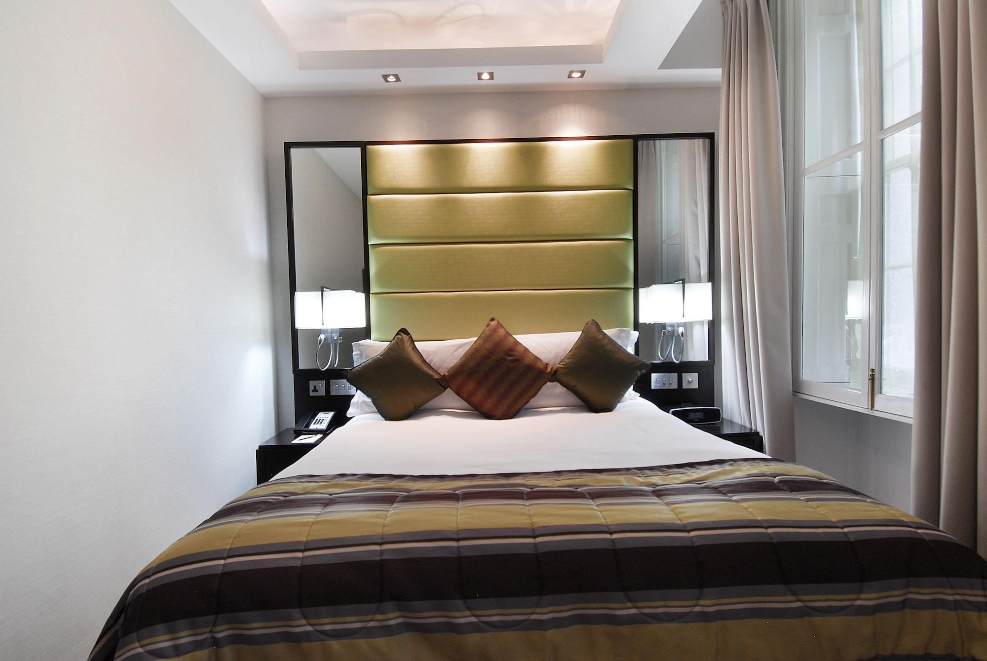 Montcalm Brewery Townhouse Hotell London Eksteriør bilde The photo shows a stylishly decorated bedroom. The bed is centered in the room, featuring a white comforter with a plaid pattern in shades of brown and green. There are three decorative pillows on the bed, two in shades of brown and one in dark green