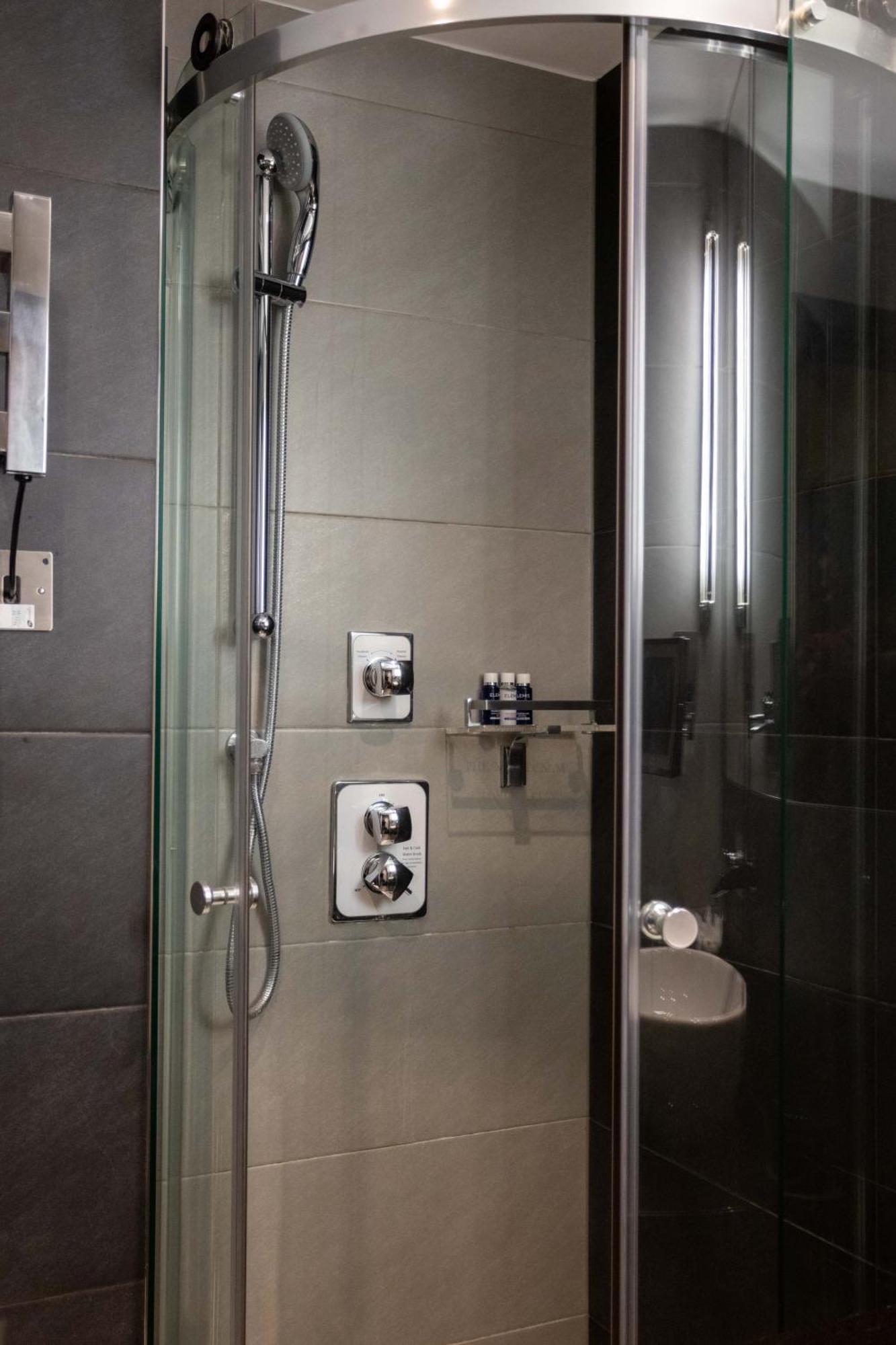 Montcalm Brewery Townhouse Hotell London Eksteriør bilde The photo shows a modern shower area. It features glass panels and tiled walls in a neutral color palette, creating a sleek and contemporary look. There are two main control panels for adjusting the water temperature and pressure, with various knobs 