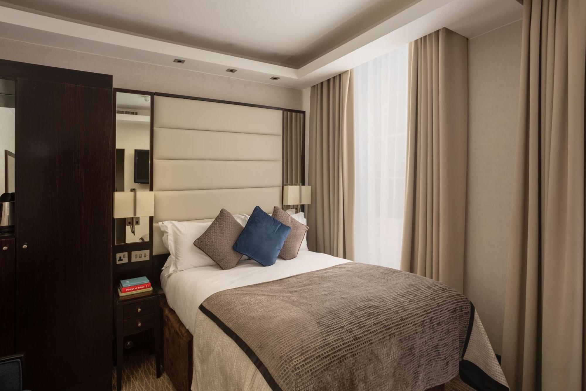 Montcalm Brewery Townhouse Hotell London Eksteriør bilde The photo shows a modern hotel room with a cozy design. It features a double bed with a light-colored headboard and a soft, stylish blanket. There are decorative pillows on the bed, including a blue one. On either side of the bed, there are small nig