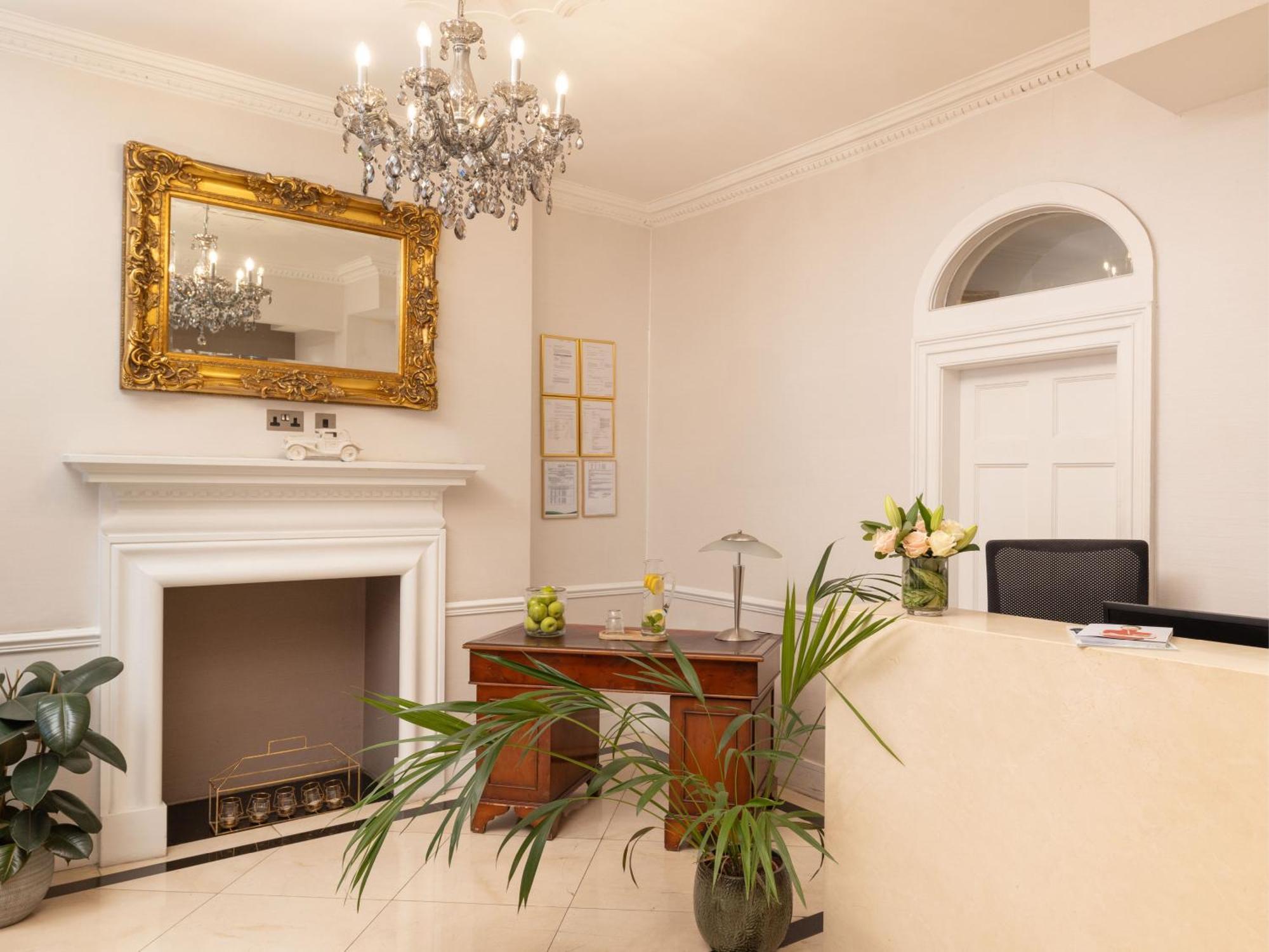 Montcalm Brewery Townhouse Hotell London Eksteriør bilde The photo shows a stylish reception area. There is a decorative chandelier hanging from the ceiling, providing elegant lighting. A large, ornate mirror is mounted on the wall beside the fireplace, which features a simple, classic design. In front of 
