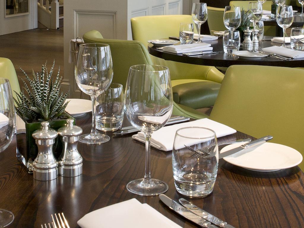 Montcalm Brewery Townhouse Hotell London Eksteriør bilde The photo shows a dining setup in a restaurant. There are tables with a polished wooden surface and elegant place settings. Each setting includes multiple wine glasses and water glasses, neatly arranged with folded napkins. 

In the center, there are