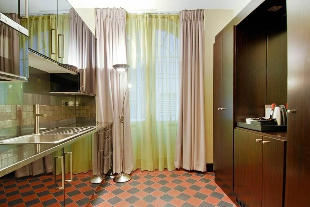 Montcalm Brewery Townhouse Hotell London Eksteriør bilde The photo shows a modern kitchen area. There is metallic cabinetry and a stainless steel countertop with a sink. The walls are adorned with light-colored curtains that allow natural light to filter in, with one set in a soft purple hue and another in