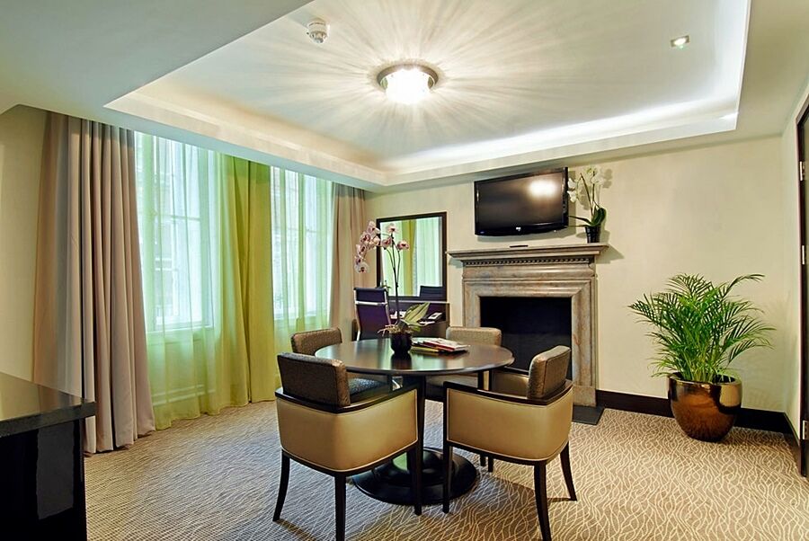 Montcalm Brewery Townhouse Hotell London Eksteriør bilde The photo shows a well-furnished room, likely a hotel suite or a modern living space. It features a round dining table with four comfortable chairs. The walls are adorned with light-colored decor, and there are large windows with sheer and solid curt