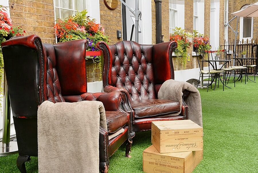 Montcalm Brewery Townhouse Hotell London Eksteriør bilde The photo depicts two large, elegant armchairs with a classic design, featuring rich burgundy leather upholstery and button tufting. They are positioned in a cozy outdoor setting, with lush green artificial grass beneath them. Next to the chairs, the